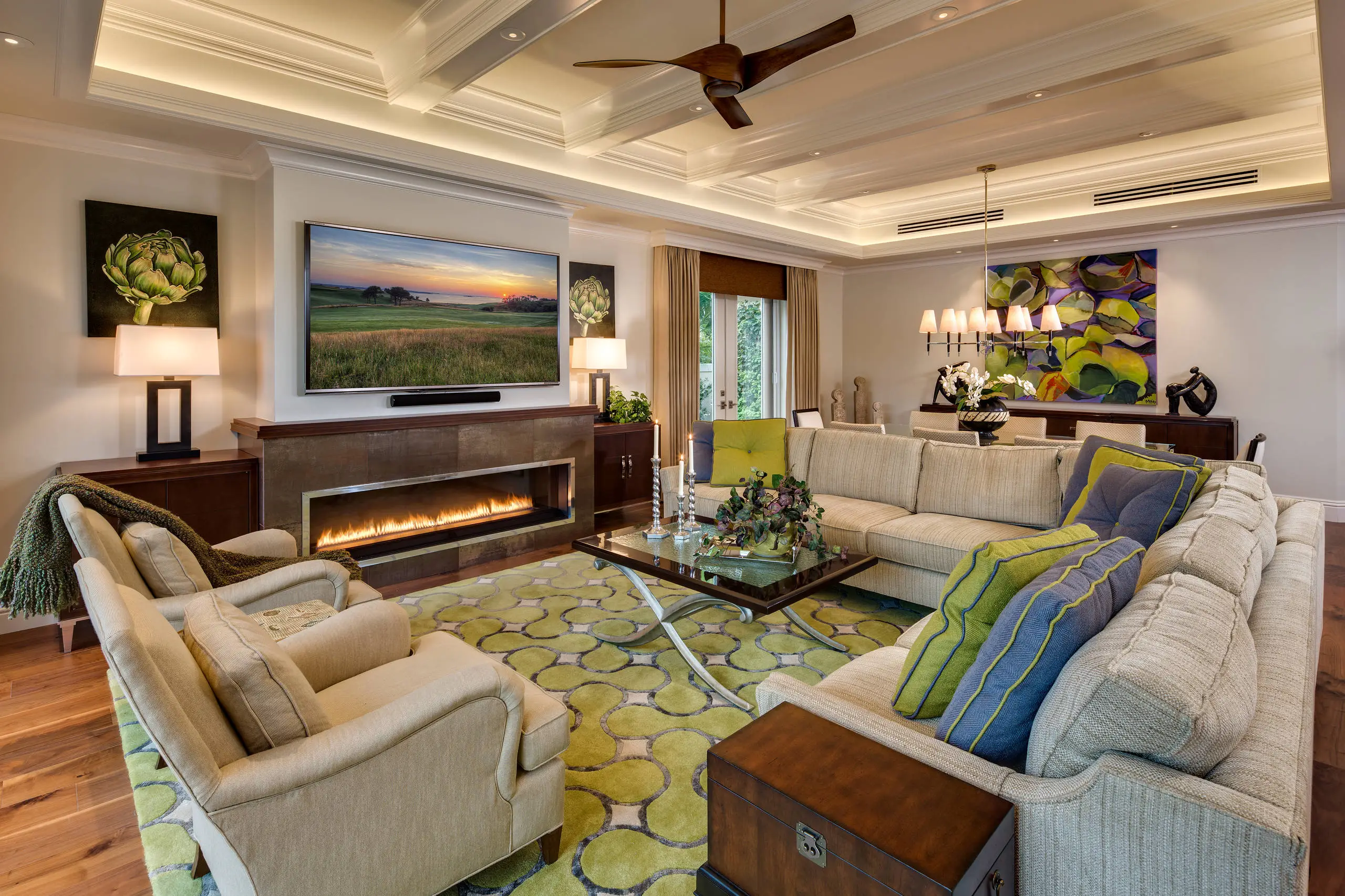 Elegant living room with beige sectional sofa, blue and green striped throw pillows, a patterned green and cream rug, coffee table